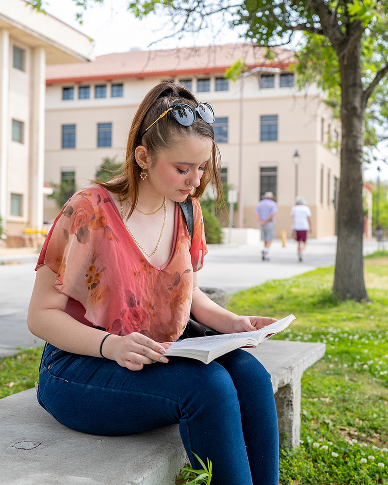 Woman studying outside a building on campus